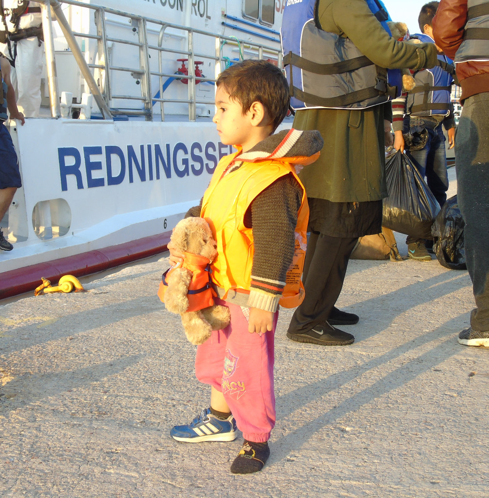 Bildet viser et barn i Middelhavet som holder bamsen Kai